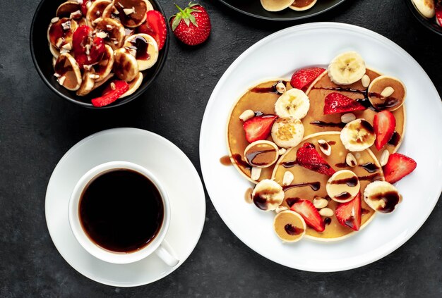 Mini panqueques con fresas y plátanos en platos sobre la mesa