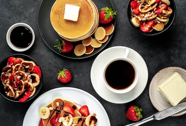 Mini panqueques con fresas y plátanos en platos sobre la mesa