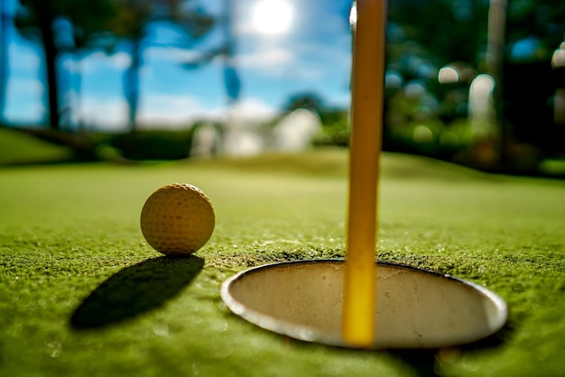 Mini pelota de golf amarilla sobre hierba verde al atardecer