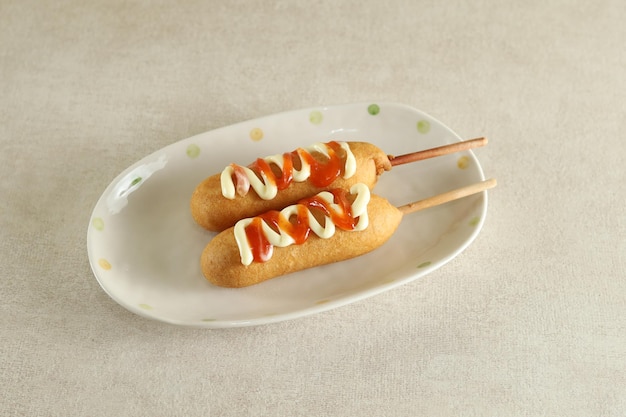 Mini perros de maíz en un plato blanco con ketchup Comida callejera coreana