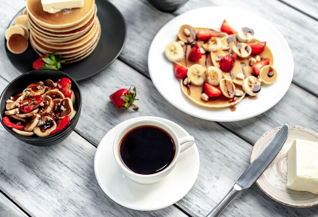 Mini-Pfannkuchen mit Erdbeeren und Bananen auf einem Teller auf dem Tisch