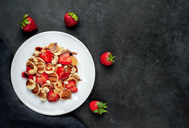 Mini-Pfannkuchen mit Erdbeeren und Bananen auf einem Teller
