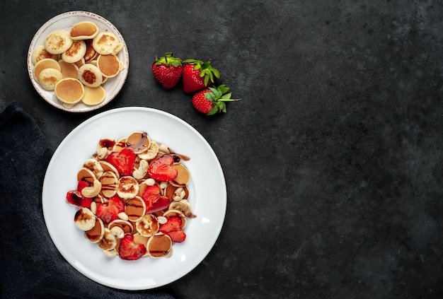 Mini-Pfannkuchen mit Erdbeeren und Bananen auf einem Teller