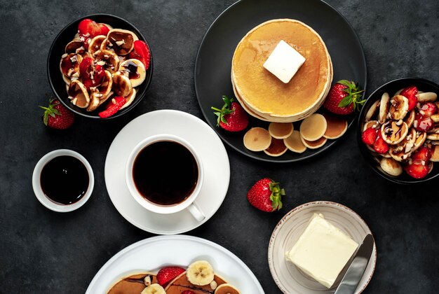 Mini-Pfannkuchen mit Erdbeeren und Bananen auf Tellern auf dem Tisch