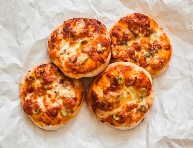 Mini pizza com azeitonas de presunto e mozzarella um delicioso lanche tapas em um fundo claro vista de cima