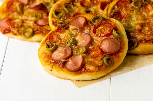 Mini pizza com salsichas e tomates em um fundo claro