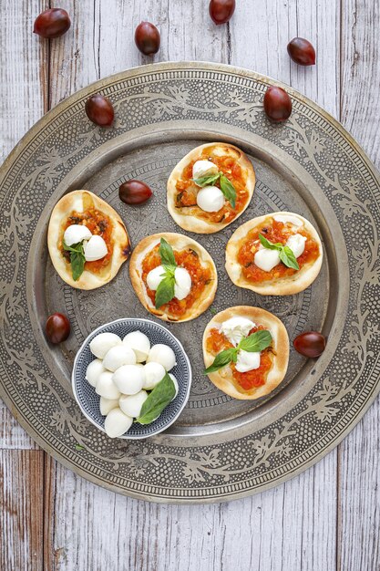 Mini pizzas margarita caseras con tomate, mozzarella y albahaca