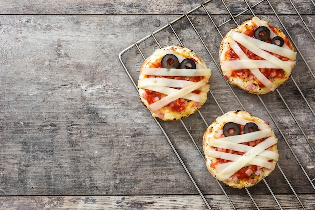 Mini pizzas de momias de Halloween en mesa de madera