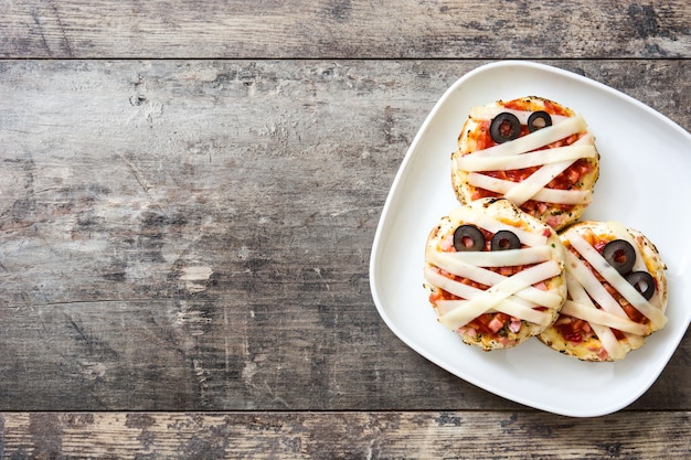 Mini-Pizzen der Halloween-Mumien auf Holztisch