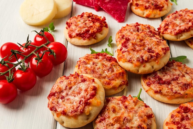 Mini-Pizzen, Salami mit Mozzarella-Käse auf einer weißen Tischplatte, ohne Menschen