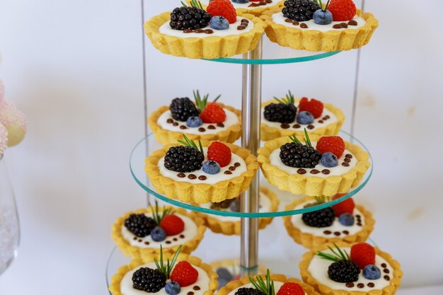 Mini postre de tartas de frutas sobre soporte acrílico escalonado. De cerca.