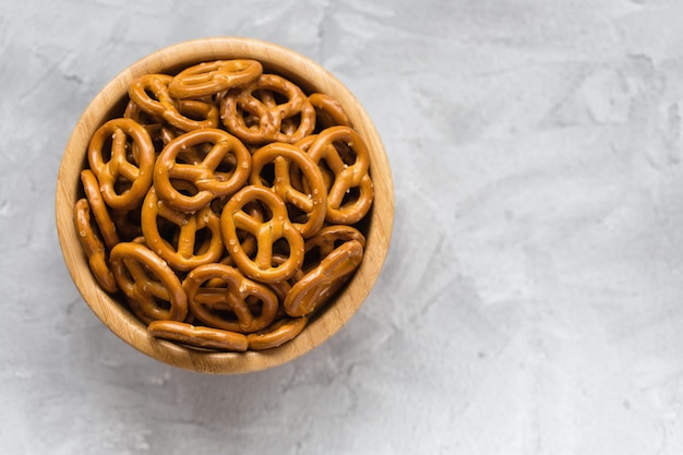 Mini pretzels salgados tradicionais em tigela de madeira em um fundo cinza Copie o espaço
