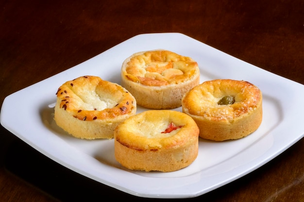 Mini quiches bocadillos de sabores variados en un plato blanco