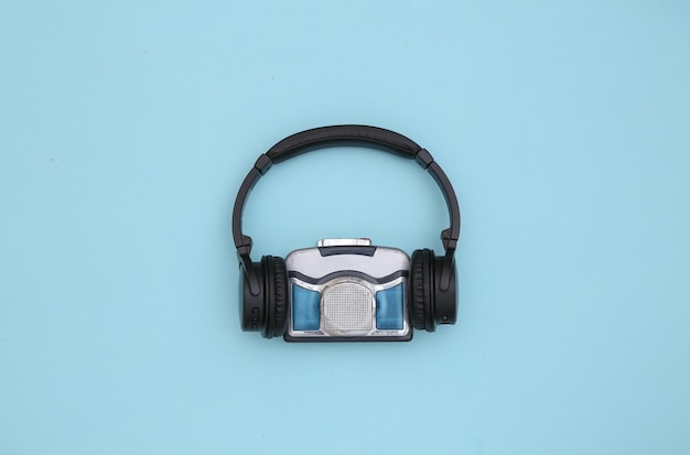 Mini reproductor de casetes de audio con auriculares estéreo sobre un fondo azul. Vista superior