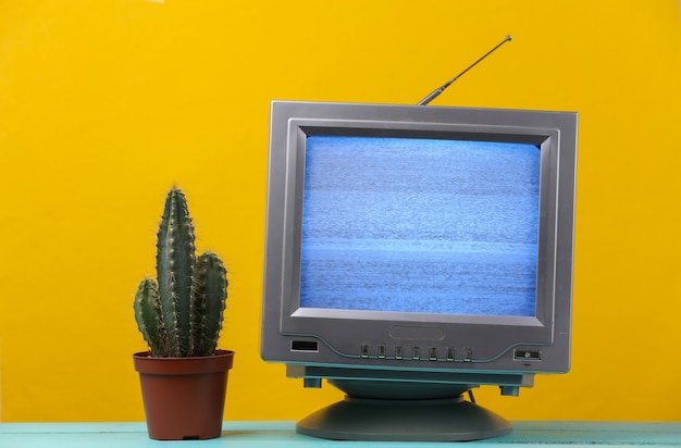 Mini Retro-TV-Antennenempfänger auf Gelb. Altmodischer Fernseher mit Kaktus.