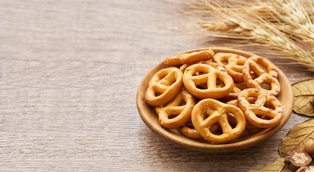 Mini-Salzbrezel in einer Holzplatte auf Holztischhintergrund.