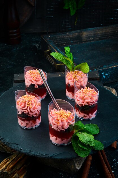 Mini sobremesa cremosa de morango em uma xícara Barra de chocolate Em uma vista superior de fundo de pedra preta