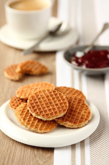 Mini stroopwafels (jarabes) en un plato con una taza de café y mermelada