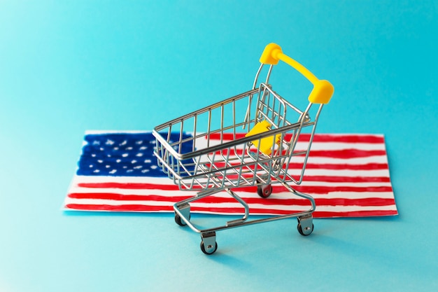 Mini Supermarkt Einkaufswagen und abstrakte Hand gezeichnete amerikanische Flagge auf gelbem Hintergrund