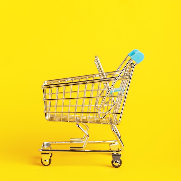 Mini-Supermarktwagen auf gelbem Hintergrund Einkaufskonzept
