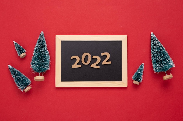 Mini-Tafel mit Weihnachtsbaum auf rotem Hintergrund Tafel mit 2022 Neujahr Weihnachtsstillleben