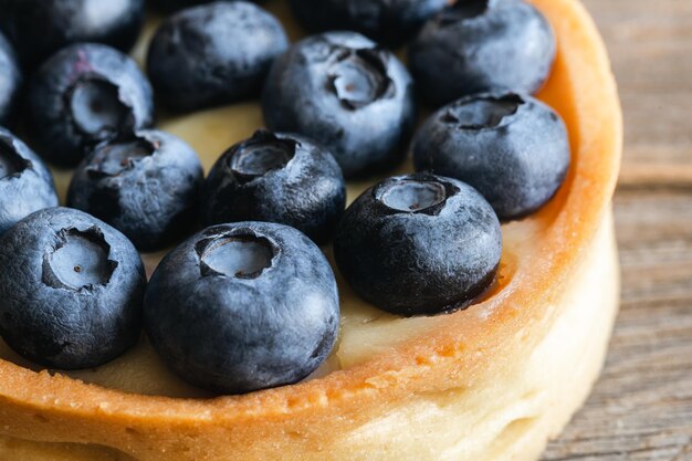 Mini tarta casera con arándanos y crema batida sobre un fondo de madera de cerca