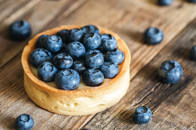 Mini tarta casera con arándanos y crema batida sobre un fondo de madera de cerca