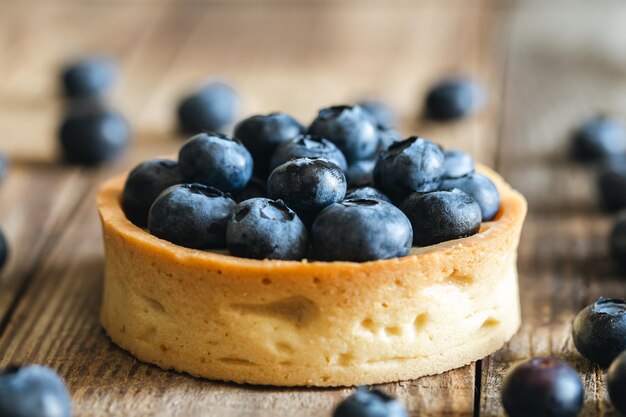 Mini tarta casera con arándanos y crema batida sobre un fondo de madera de cerca