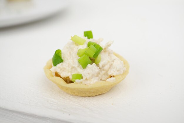 Una mini tartaleta con pasta de pescado espolvoreada con cebolla fresca