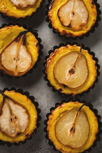 Mini tartas de peras y natillas en una vieja mesa de hormigón gris oscuro.