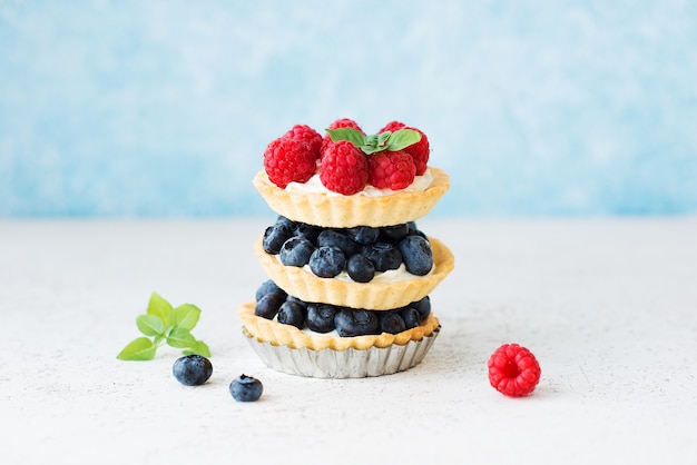 Mini tartas de postre con crema y frutos rojos, cestas con arándanos y frambuesas