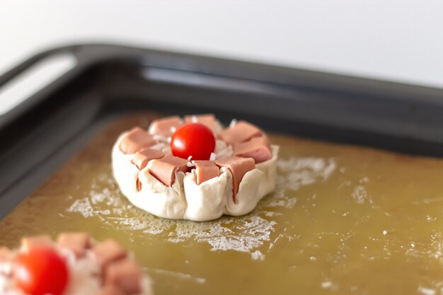 Mini torta de massa folhada crua com linguiça, queijo e tomate cereja pronta para assar.