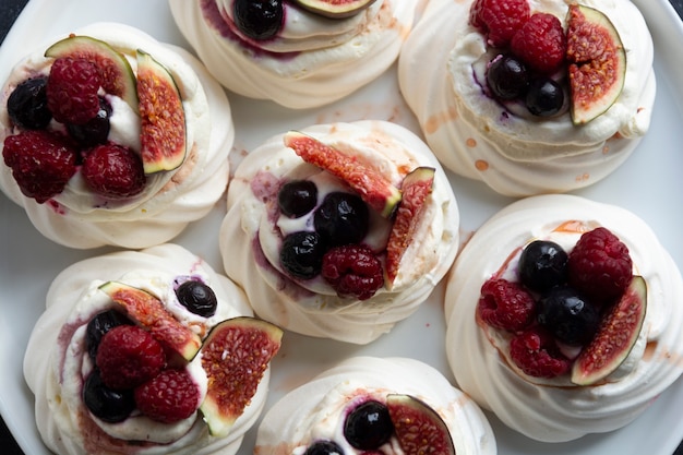 Mini tortas de merengue Pavlova decoradas con frutos rojos e higos