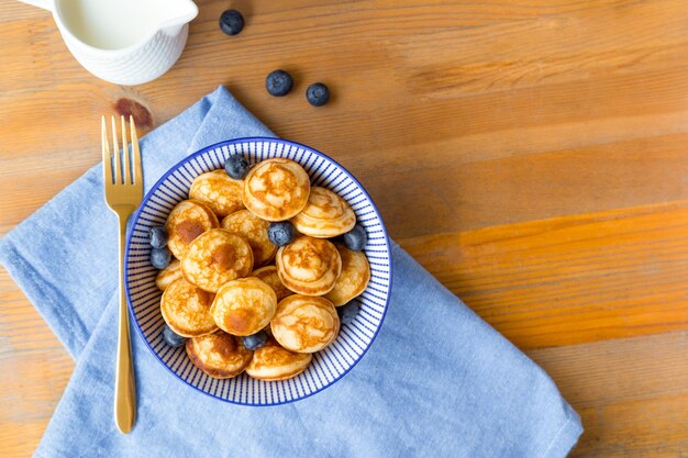 Mini tortitas de cereales con frutos rojos en mesa de madera. Concepto de comida de moda, hora del desayuno para niños. Menú, receta, vista superior o plano