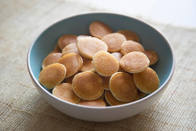 Mini tortitas de cereales con mantequilla y frutos rojos en un bol.