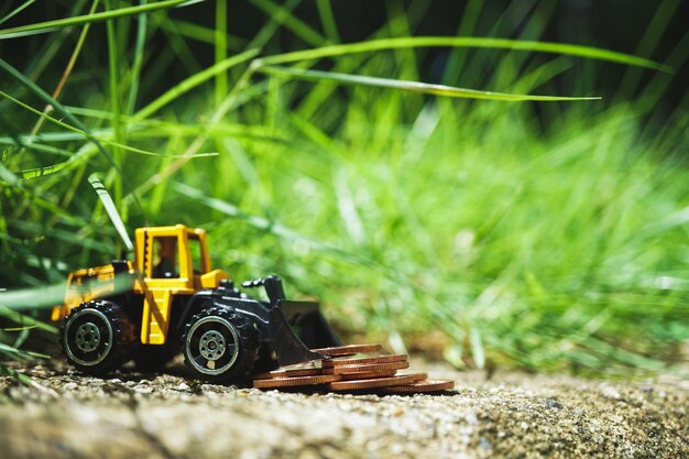 El mini tractor del primer con las monedas de la pila en la tierra usando como negocio, concepto industrial