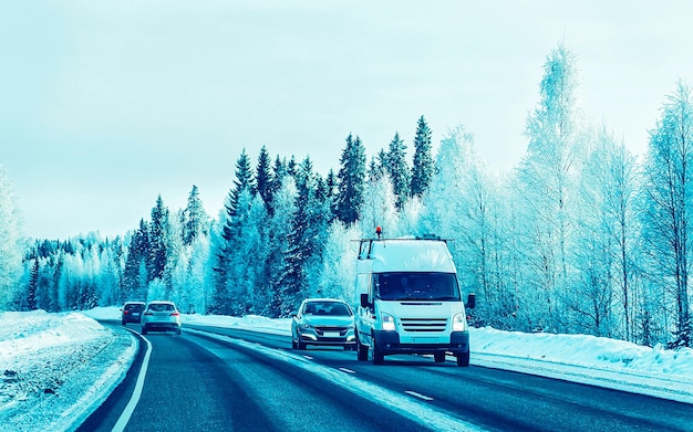 Mini Van und Autos fahren auf Winterstraßen mit Schnee in Finnland. Kalte Landschaft Lapplands. Europa Wald. Finnische Autobahnfahrt. Fahrbahn und Route auf schneebedeckter Reise.