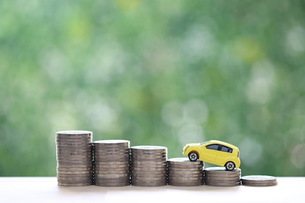 Miniatur-Automodell auf wachsendem Stapel von Münzen Geld auf grünem Hintergrund der Natur Geld sparen für Autofinanzierung und Autokredit Investitions- und Geschäftskonzept