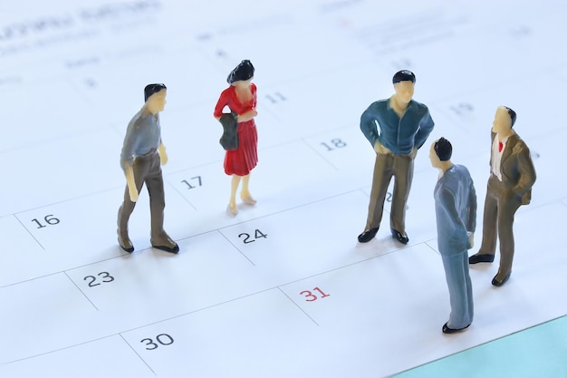 Miniatur-Mannequin-Leute Geschäftsmann, der im Besprechungskonzept auf dem Kalender steht