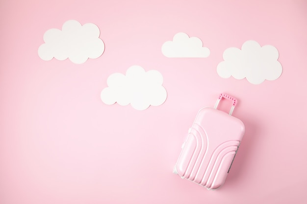 Miniatur rosa Koffer über rosa Hintergrund