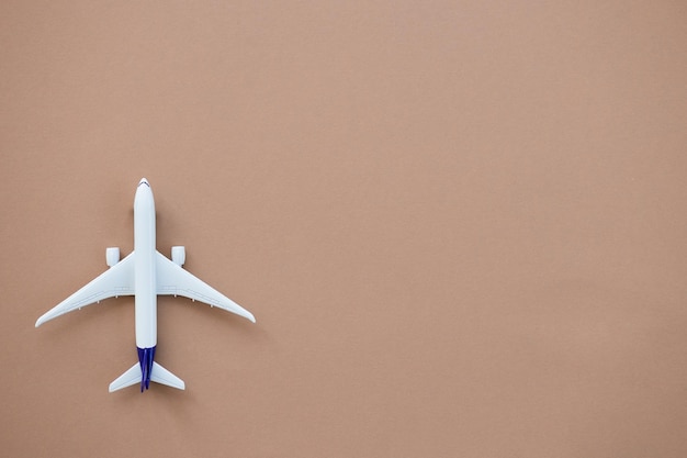 Miniatur-Spielzeugflugzeug auf beigem Hintergrund Sommerurlaub Flugreisen mit dem Flugzeug Konzept