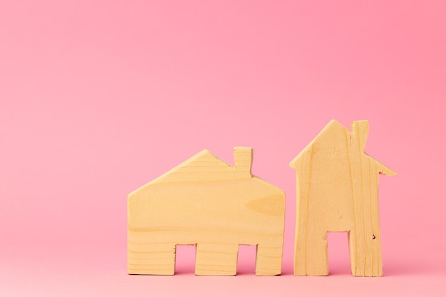 Miniatura de casa de madera sobre fondo rosa de cerca
