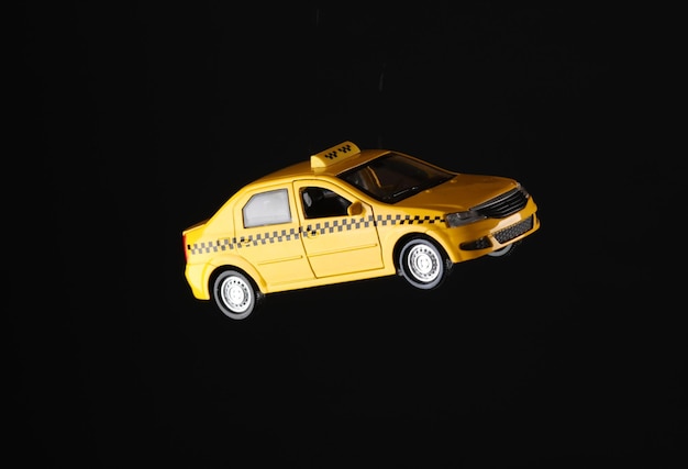 Miniatura de coche de taxi amarillo aislado sobre un fondo negro