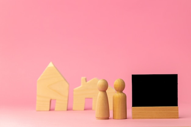 Miniatura de casa de madeira e pessoas de brinquedo em fundo rosa close-up