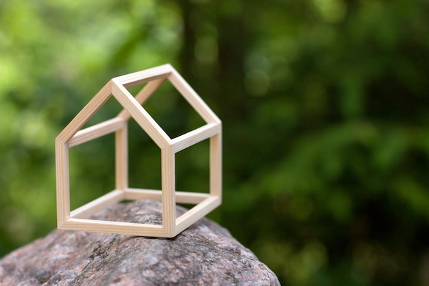 Miniatura de casa de madeira em pé na floresta. Imagem do conceito da minha casa. Conceito de hipoteca