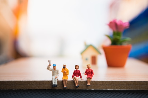 Miniatura de pessoas, homem e mulher sentada no fundo de madeira, usando como conceito de relaxamento