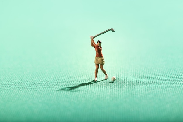 Miniatura mulher jogando golfe em um verde