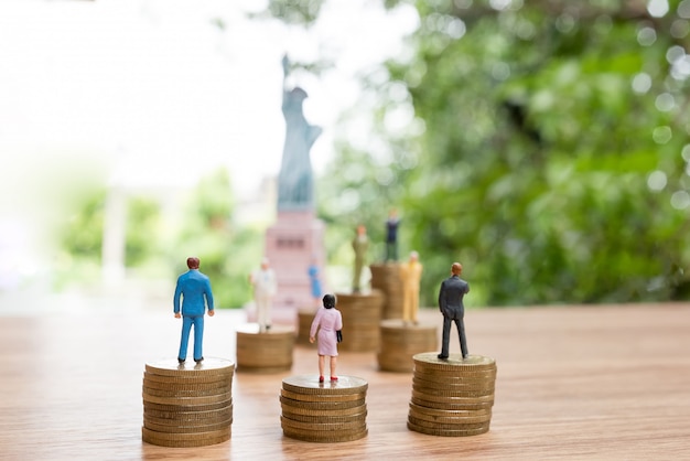Miniatura pessoas em pé na moeda com a estátua da liberdade