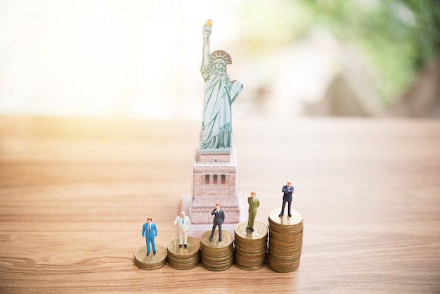 Miniatura pessoas em pé na moeda com a estátua da liberdade