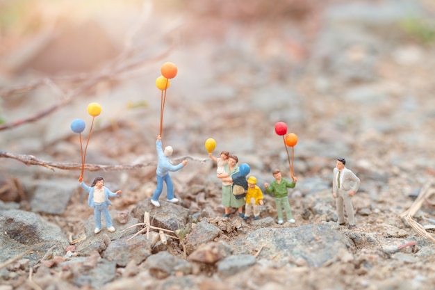 Miniatura pessoas: família feliz andando em campo com balões